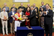 Executive Director of the Oriental Watch Holdings Limited Mr Alain Lam Hing Lun, accompanied by his wife (right), presents a souvenir to jockey Karis Teetan.